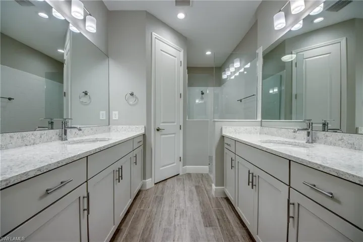 Dual vanity bathroom featuring light-toned cabinetry, polished chrome fixtures, and quartz countertops