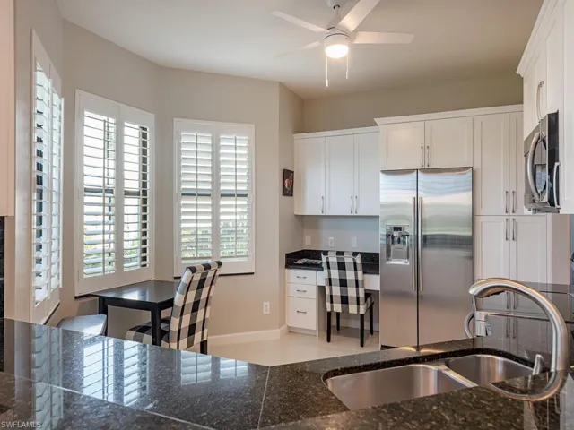 Kitchen featuring white cabinetry, appliances with stainless steel finishes, built in desk, and sink