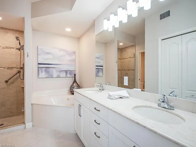 Bathroom featuring tile patterned floors, vanity, and plus walk in shower