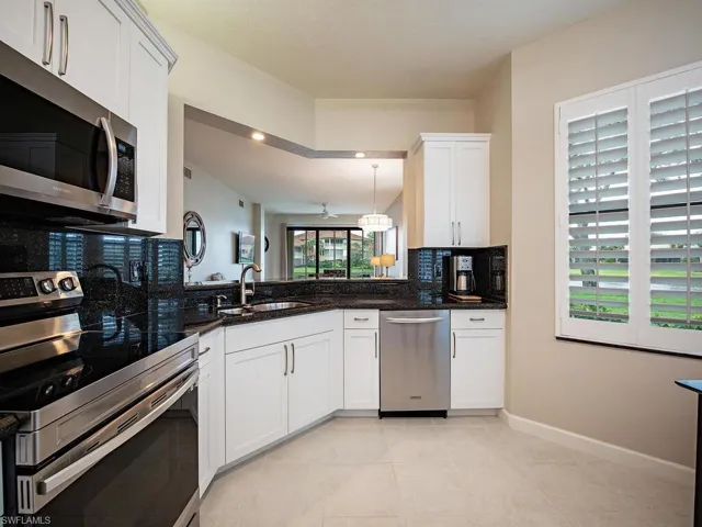 Kitchen featuring white cabinetry, stainless steel appliances, decorative backsplash, sink, and light tile patterned floors