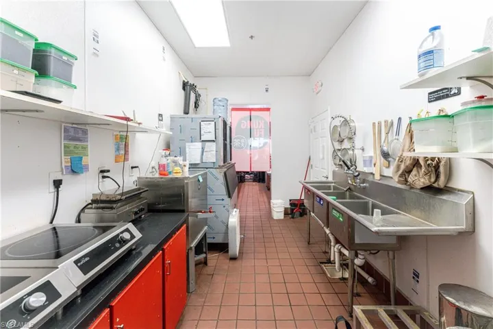 Kitchen featuring tile patterned flooring, stovetop, and white cabinetry