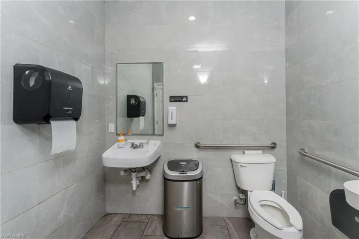 Bathroom featuring sink, toilet, and tile walls