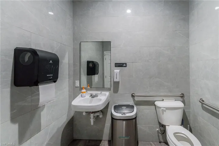 Bathroom with sink, toilet, and tile walls