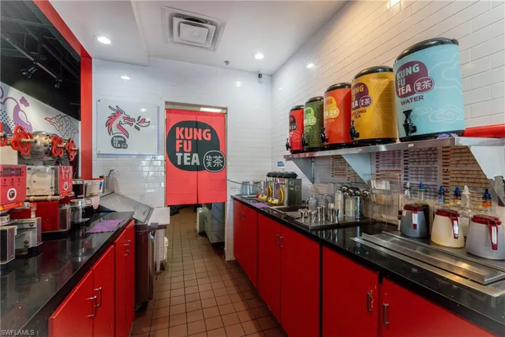 Kitchen with dark tile patterned flooring, stainless steel stovetop, and tile walls