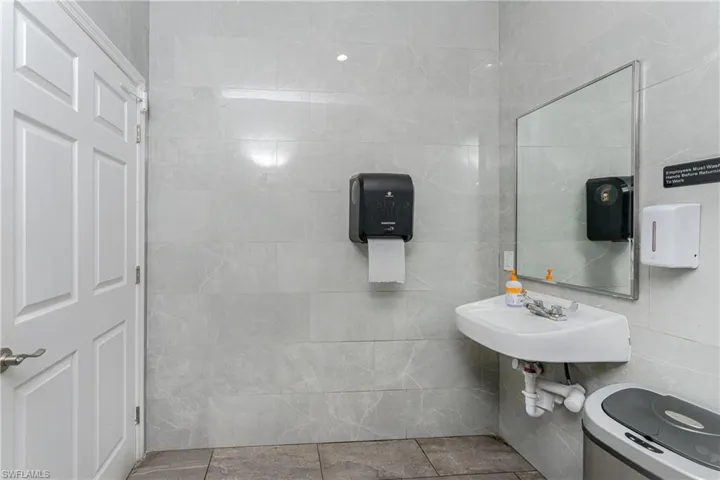 Bathroom featuring tile patterned floors, sink, and tile walls