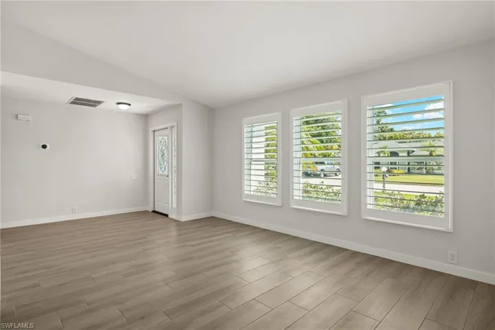 Unfurnished room featuring light wood-type flooring and vaulted ceiling