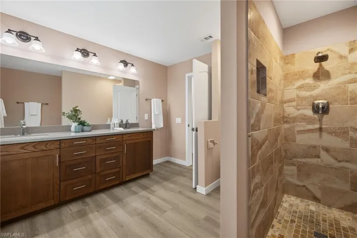 Primary Bathroom with a tile shower, vanity, and hardwood / wood-style flooring