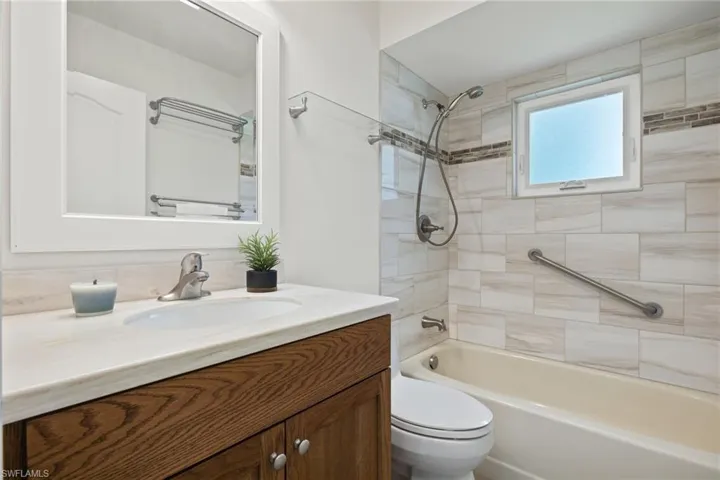 Full bathroom with tiled shower / bath combo, vanity, and toilet