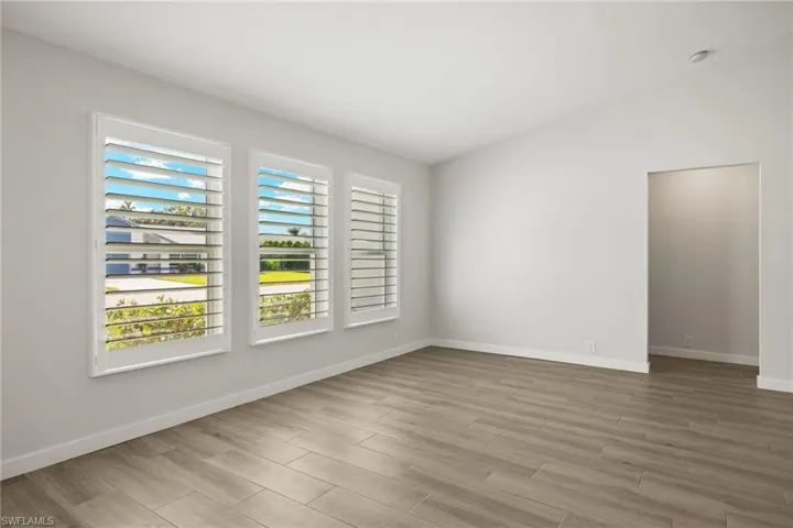 Empty room with vaulted ceiling and light hardwood / wood-style flooring