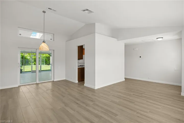 Unfurnished living room featuring light hardwood / wood-style floors, a skylight, and high vaulted ceiling