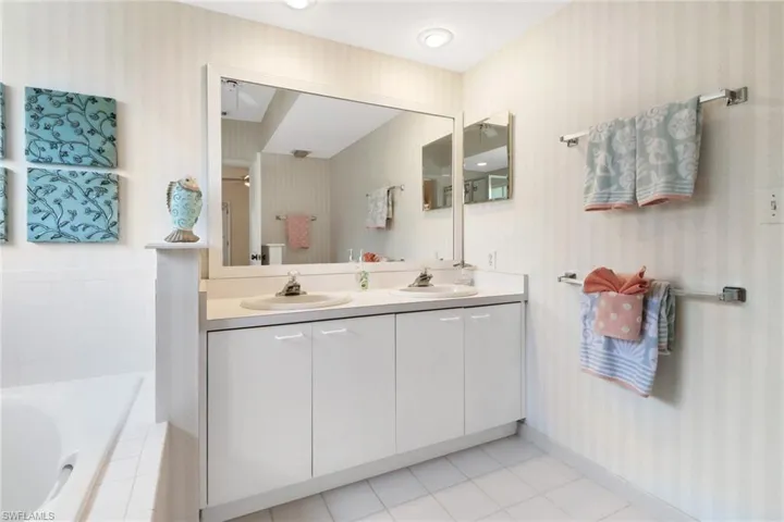 Master bathroom with tiled bath, separate shower, tile flooring, and double vanity