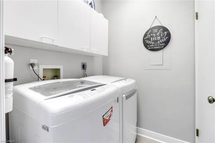 Laundry room featuring washing machine, clothes dryer and storage cabinets