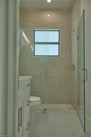 Bathroom featuring tile walls, toilet, tile floors, a shower with shower door, and vanity