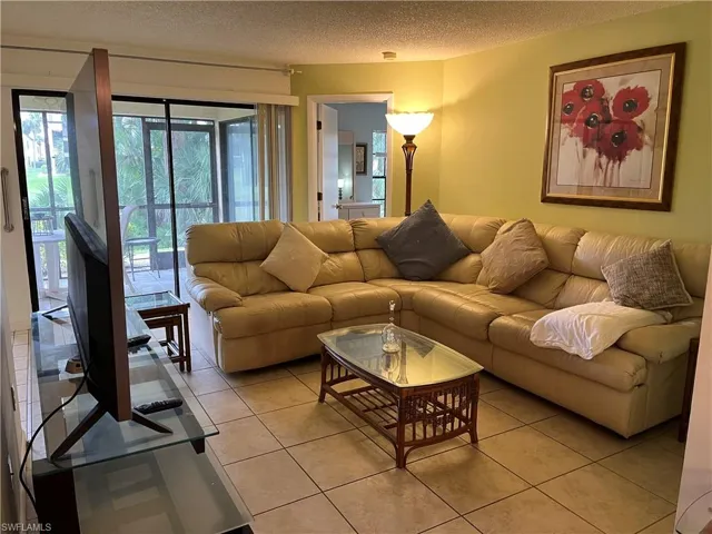 Living area featuring light tile patterned flooring and a textured ceiling