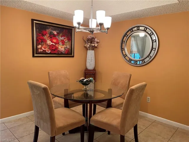 Dining space featuring a chandelier, a textured ceiling, and light tile patterned floors
