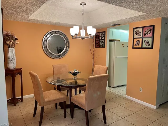 Dining space with a textured ceiling, a chandelier, and light tile patterned floors