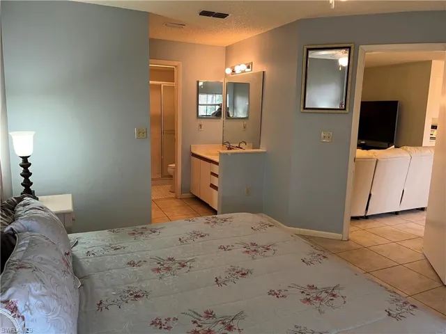 Bedroom with light tile patterned floors and ensuite bath