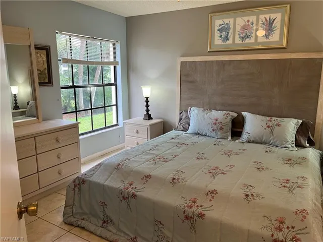 Bedroom featuring multiple windows, light tile patterned flooring, and a textured ceiling
