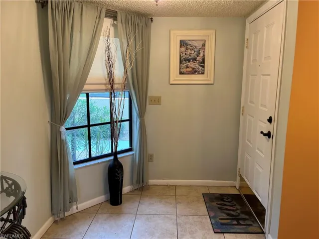 Foyer entrance with light tile patterned flooring and a textured ceiling