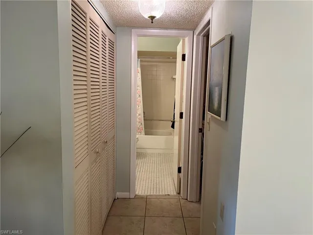 Corridor featuring a textured ceiling and tile patterned flooring