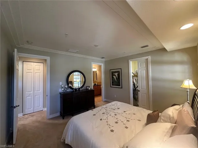 Bedroom with carpet, a spacious closet, ornamental molding, a textured ceiling, and ensuite bathroom