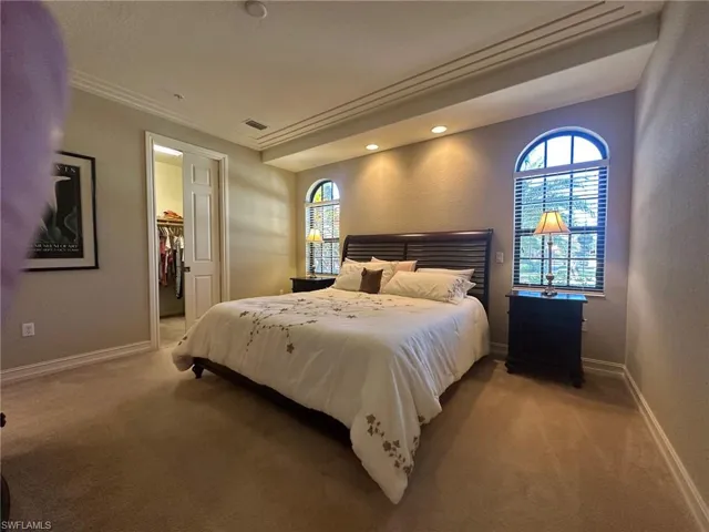 Bedroom featuring a spacious closet, recessed lighting, crown molding, and carpet flooring