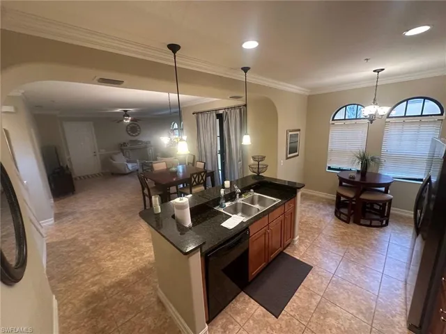 Kitchen with arched walkways, freestanding refrigerator, ornamental molding, a chandelier, and open floor plan