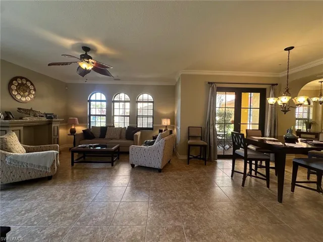 Living room with a chandelier, plenty of natural light, ornamental molding, ceiling fan, and tile patterned flooring