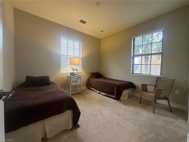 Bedroom with light colored carpet and multiple windows