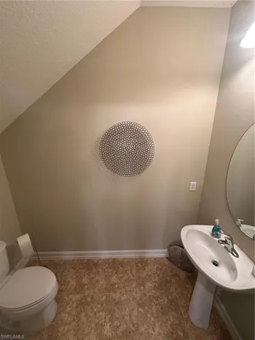 Half bathroom with vaulted ceiling and a textured ceiling