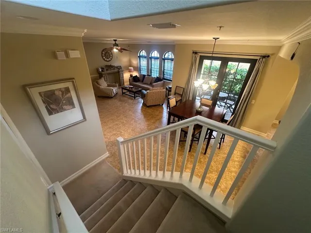 Staircase featuring crown molding, a ceiling fan, and a chandelier