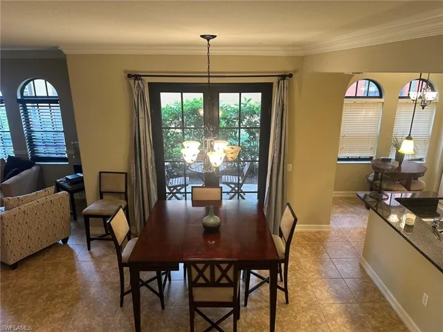 Tiled dining space with a chandelier, ornamental molding, and healthy amount of natural light