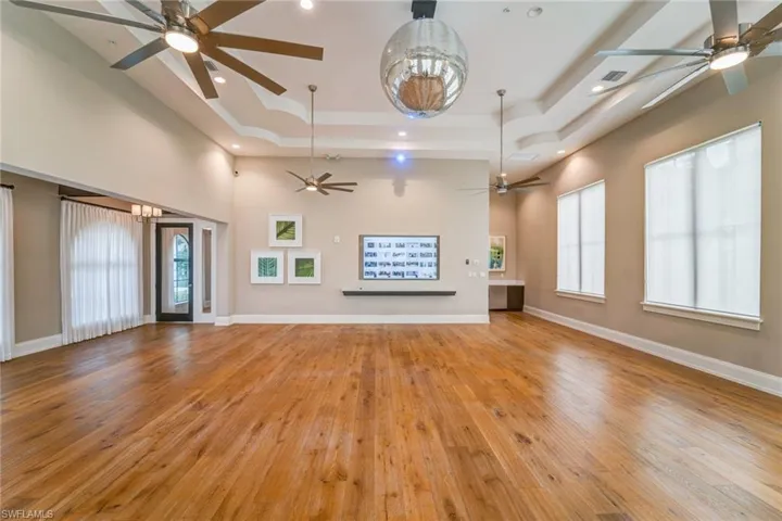 Unfurnished living room with a towering ceiling, a raised ceiling, and light hardwood / wood-style floors
