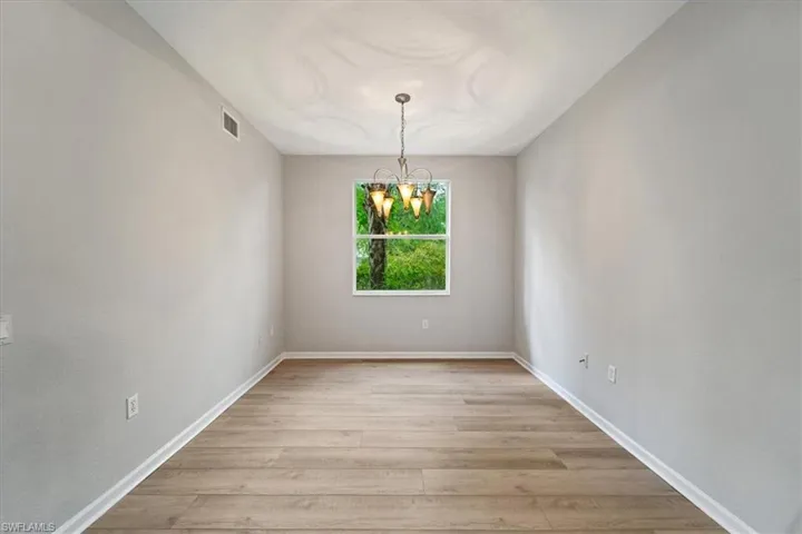 Spare room with a chandelier and light wood-type flooring