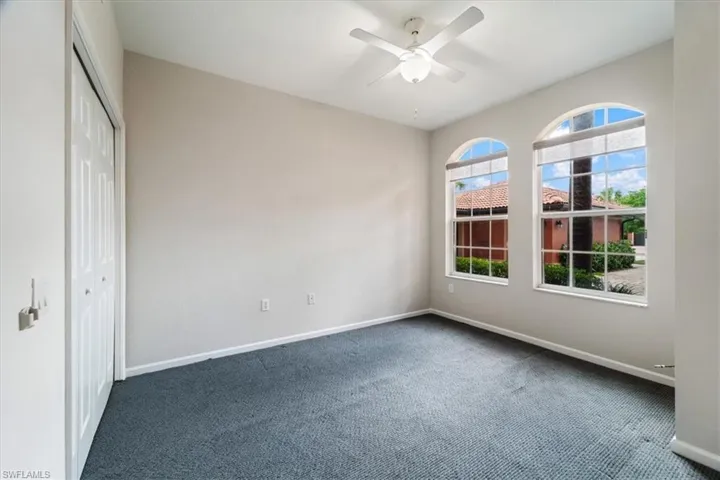 Unfurnished bedroom featuring dark colored carpet, a closet, and ceiling fan