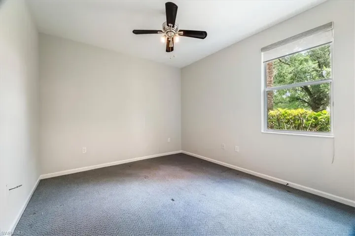 Carpeted empty room featuring baseboards and ceiling fan