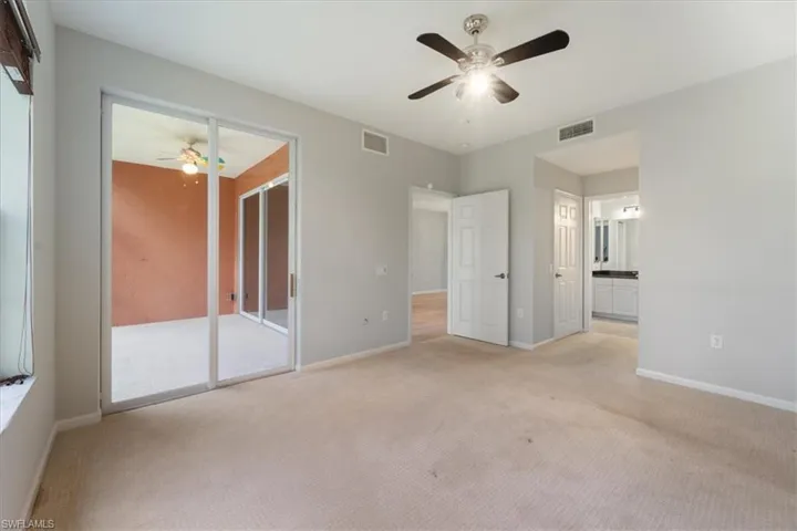 Unfurnished bedroom with light colored carpet, ceiling fan, and connected bathroom