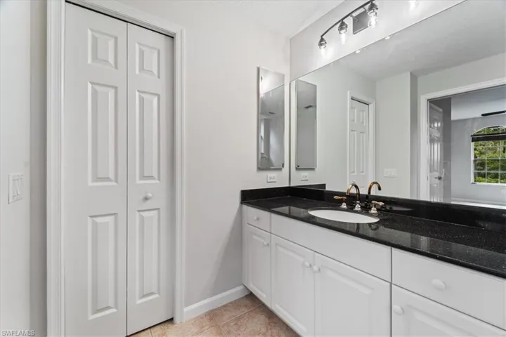 Bathroom with vanity, a closet, and tile patterned floors