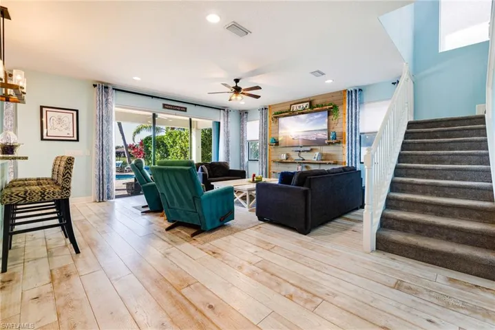 Living room with light wood-style floors, a ceiling fan, stairs, and visible vents