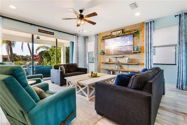 Living room with stairway, a ceiling fan, recessed lighting, and visible vents