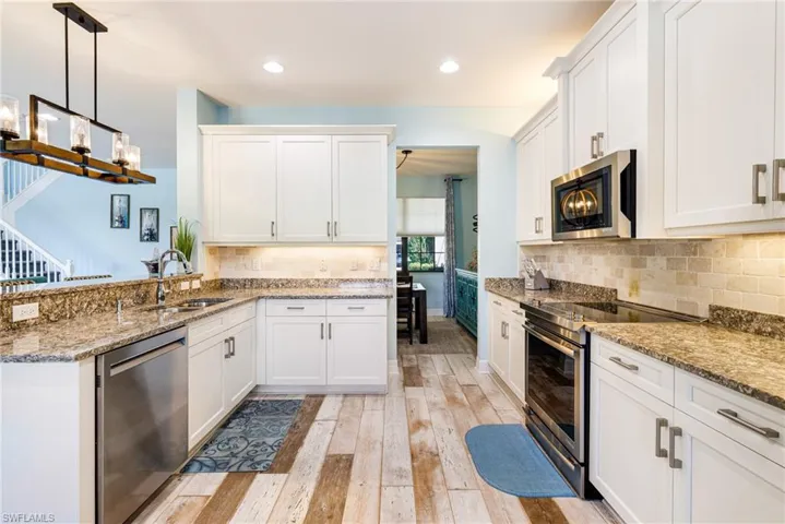 Kitchen with a sink, appliances with stainless steel finishes, light wood-style floors, and white cabinetry