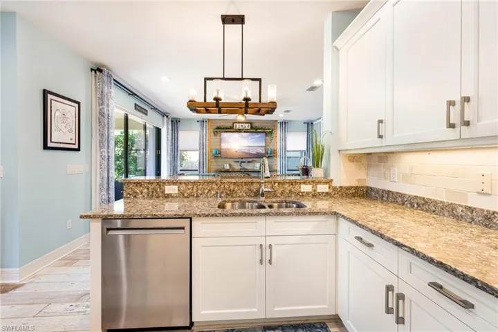 Kitchen featuring a peninsula, light wood-type flooring, tasteful backsplash, a sink, and dishwasher