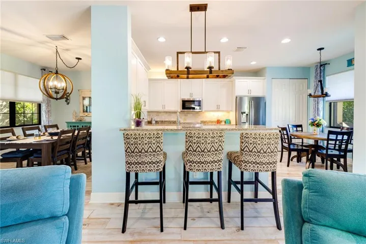 Kitchen with an inviting chandelier, a peninsula, open floor plan, a kitchen bar, and appliances with stainless steel finishes