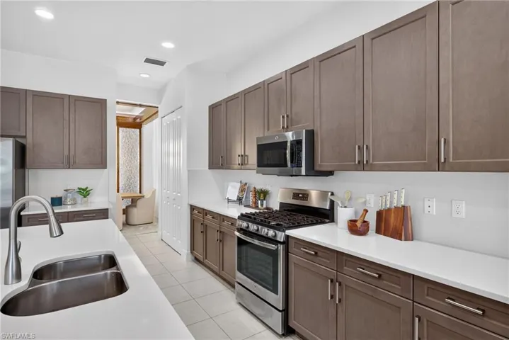Modern kitchen featuring light-toned cabinetry, stainless steel appliances, a dual basin sink, white countertops, and tile flooring