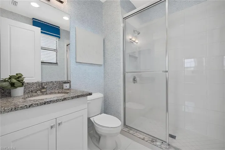 White vanity with granite countertop, integrated sink, and chrome faucet