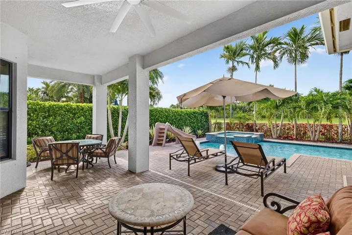 Covered patio with a ceiling fan, brick paver flooring, swimming pool, and raised spa