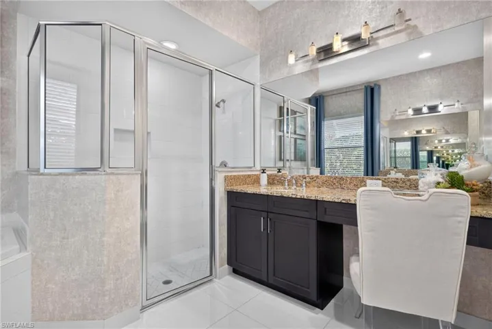 Walk-in shower with clear glass enclosure and white tile surround