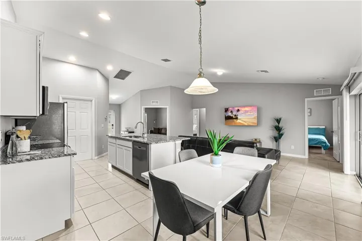 Dining space featuring vaulted ceiling, light tile patterned floors, and recessed lighting