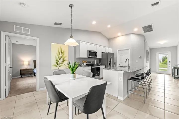 Dining space with lofted ceiling, light tile patterned floors, and recessed lighting