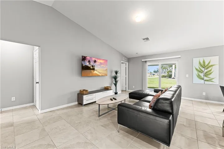 Living area with high vaulted ceiling and light tile patterned floors
